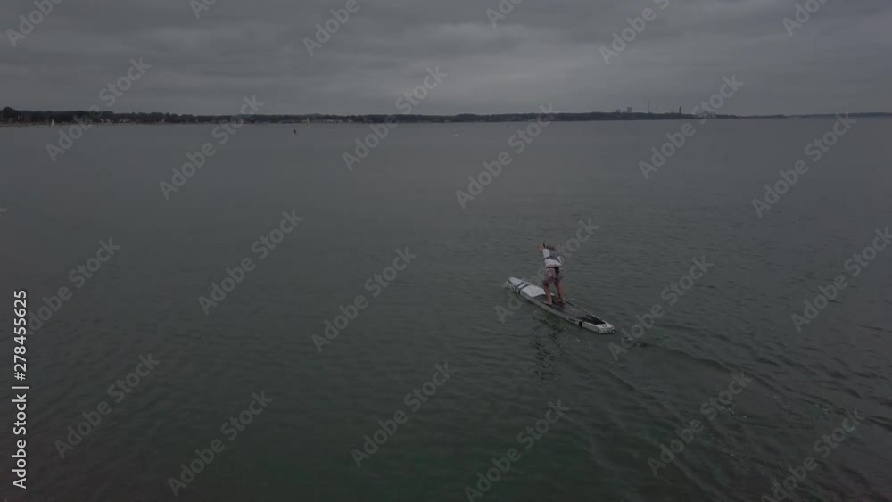 WOMEN PADDLE ON SURFBOARD AT A SEA CLOUDY WEATHER UNGRADED WOMEN PADDLE ON SURFBOARD AT A SEA CLOUDY WEATHER UNGRADED