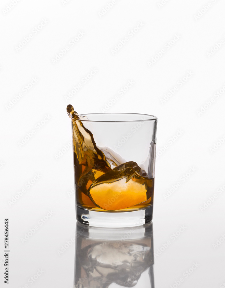 Whiskey splash on elegant glass isolated on white background Whiskey splash on elegant glass isolated on white background
