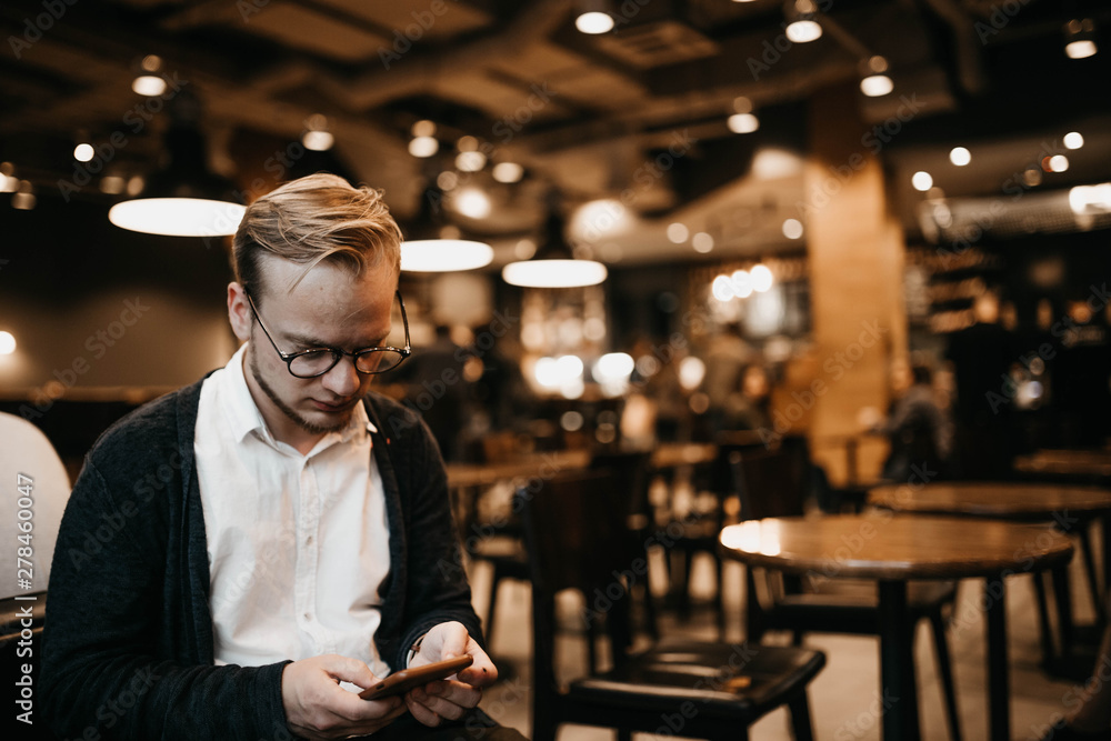 hipster man with glasses sitting in a cozy cafe