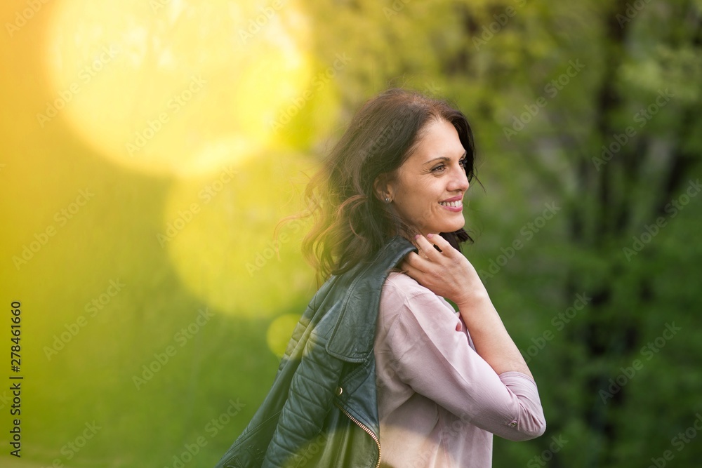 Middle-age woman in black jacket smiling, holds her jacket over the shoulder. Middle-age woman in black jacket smiling, holds her jacket over the shoulder.