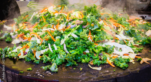 fresh vegetables steaming on a griddle for hot meals at a farmers market 
