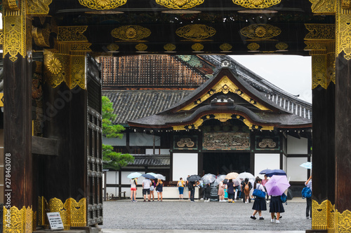 Tourists at the entrance in the Nijo castle in Kyoto in rain with colorful umbrellas during rainy season in Japan photo