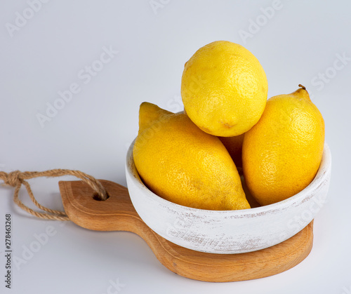 fresh ripe whole yellow lemons on a wooden board