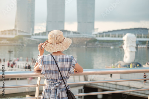 Photography Young Woman traveling with hat in the morning, happy Asian traveler visit in Singapore city downtown