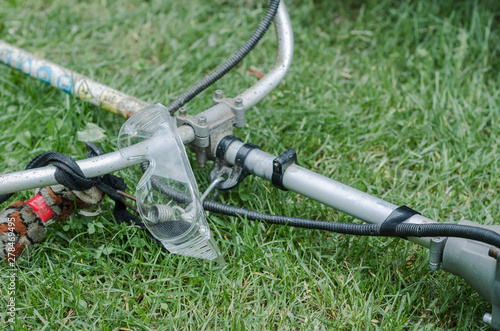 petrol lawn mower and plastic safety glasses on green grass