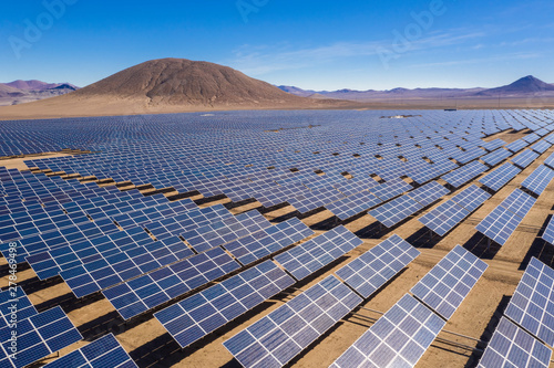 Aerial view of hundreds solar energy modules or panels rows along the dry lands at Atacama Desert, Chile. Huge Photovoltaic PV Plant in the middle of the desert from an aerial drone point of view