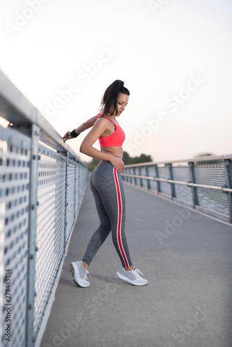 Female with fit attractive figure posing on modern bridge 
