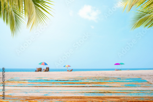 Fototapeta Naklejka Na Ścianę i Meble -  Top of wood table with seascape, palm leaf, calm sea and sky at tropical beach background. Empty ready for your product display montage.  summer vacation background concept.