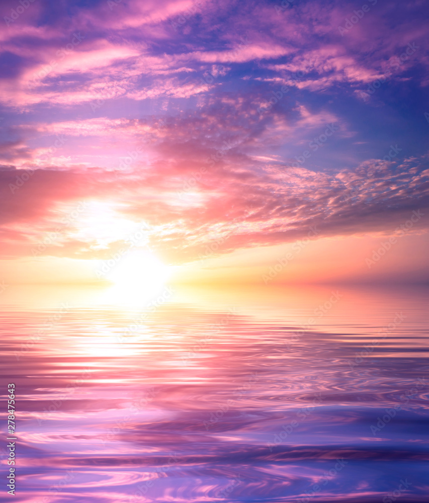 Pink sunset on the sea with reflection of clouds and the sun on the water surface.