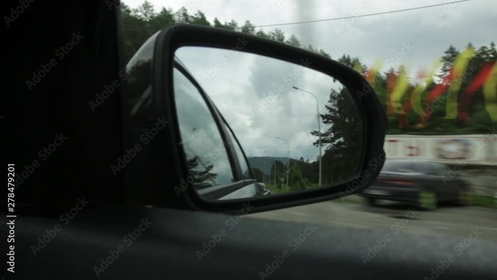 View of side mirror, reflection of a mountain road through the countryside on a summer day View of side mirror, reflection of a mountain road through the countryside on a summer day