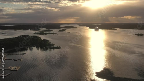 Drone flight at sunset over the Swedish Archipelago islands near Stockholm. A cruise ship is seen in the distance photo