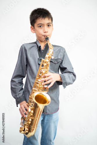 Canvas Print Little asian musician boy playing saxophone instrument