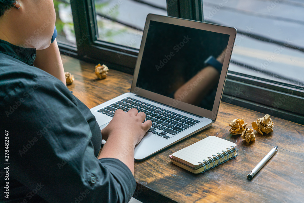 Naklejka premium Woman using laptop next to crumpled paper balls