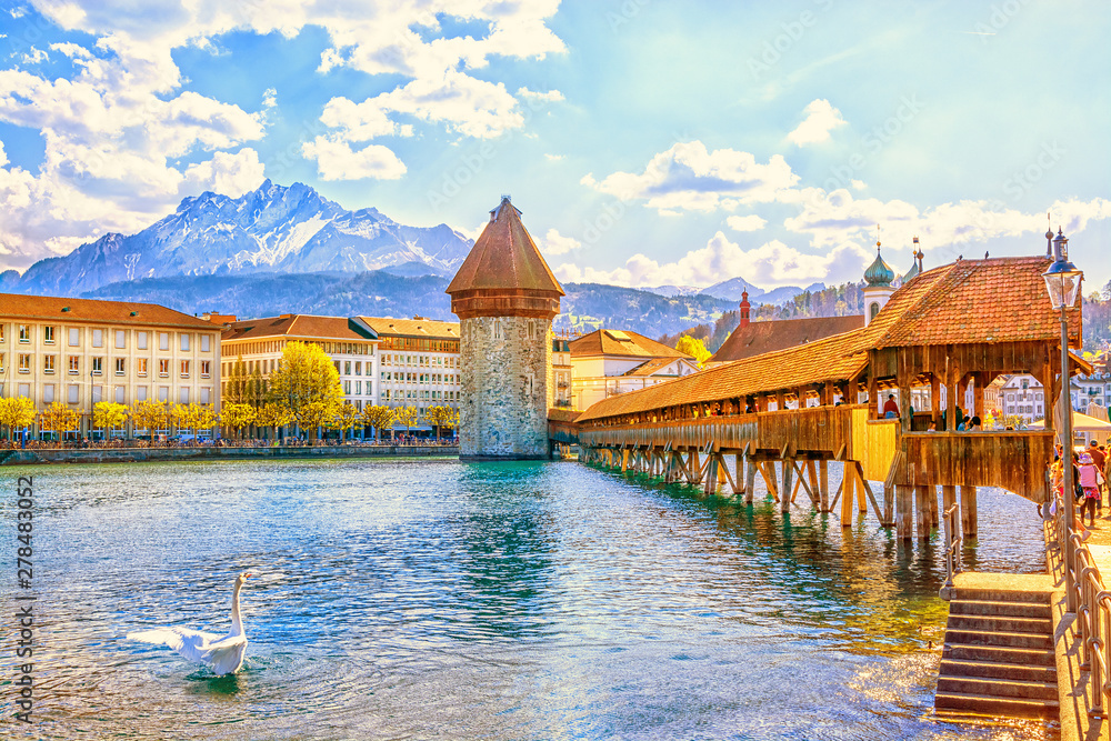 Ancient covered wooden Chapel Bridge Kapellbrucke and Water Tower Wasserturm on the background of the snow covered Pilatus Mountain in the historic center of Lucerne at sunset, Switzerland