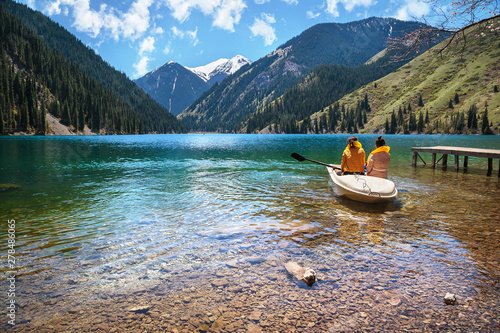 Two girls in a boat on a clear mountain lake photo