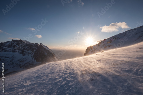 Sunset on snowy hill in blizzard at sunset