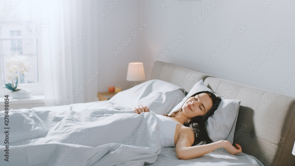 Attractive Brunette Cozily Sleeps in Her Bed while Early Morning Sunrays Illuminate Her. Warm, Cozy and Sweet Picture of Beauty Sleeping  - obrazy, fototapety, plakaty 