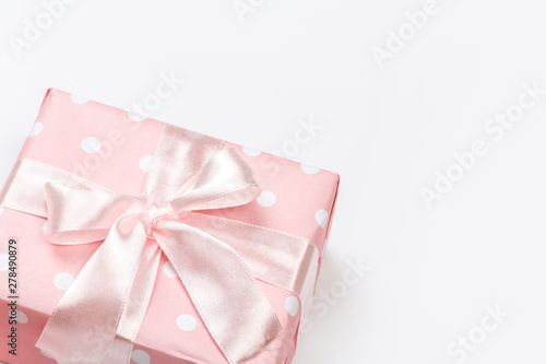 Gift box wrapped in pastel paper with pink ribbon isolated