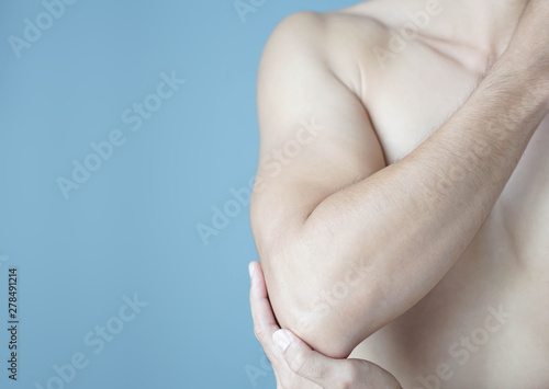 Closeup man hand holding elbow with pain with blue background, health care and medical concept