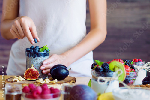 Φωτογραφία Female hands are preparing yogurt with chia and blueberries for good digestion, functioning of gastrointestinal tract