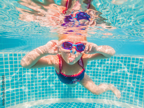 The little girl in the water park swimming underwater and smiling