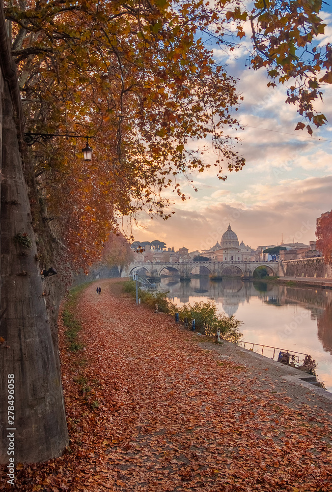 Fototapeta premium Autumn and foliage in Rome. Afternoon romantic walk along River Tiber with red and yellow leaves, in the city historic center