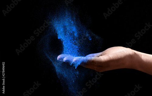 Woman Hand holding blue holi powder over black background