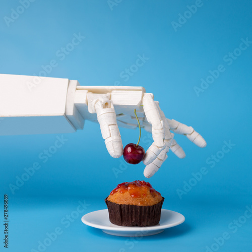 Obraz na płótnie Robot hand decorating sweet cupcake with fresh cherry