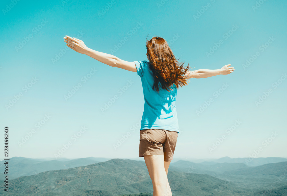 Woman standing with raised arms on background of sky and mountains. Woman standing with raised arms on background of sky and mountains.