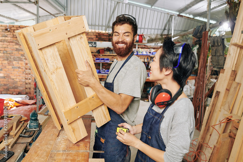 Happy multi-ethnic team of carpenters discussing new piece of furniture they made