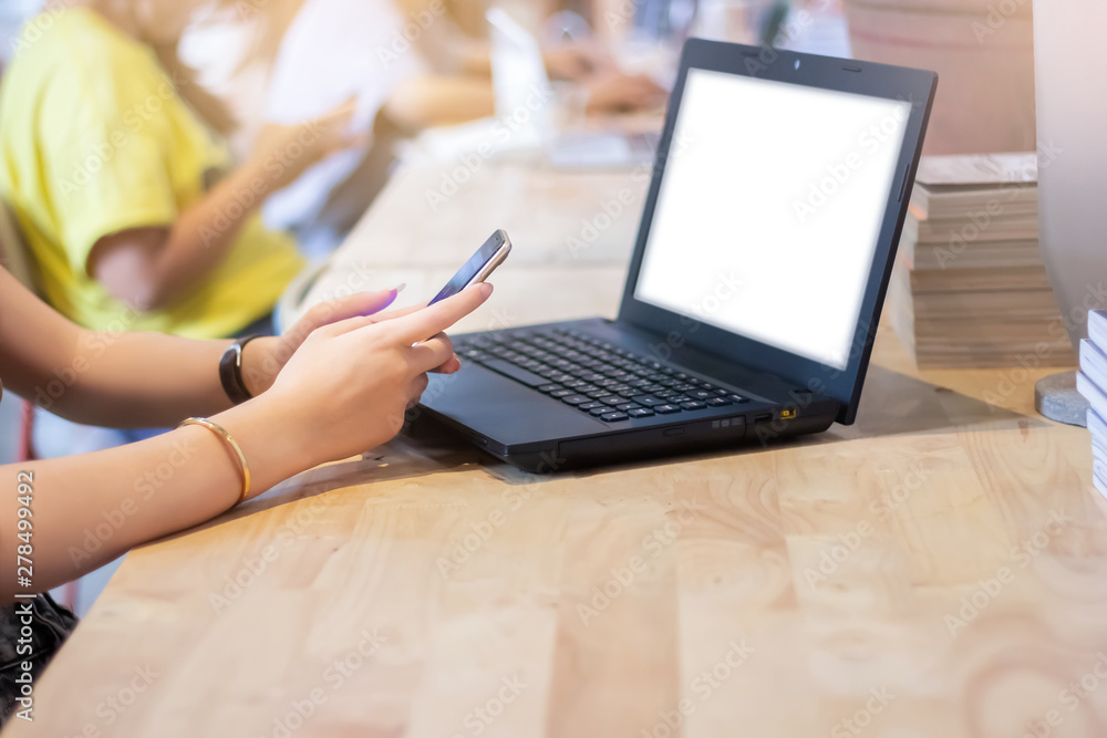 Fototapeta premium Closeup of hand young asian woman using smart and laptop for working and business communication with blurred group of people working on background