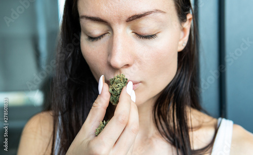 the girl holds a marijuana bud in her hands and sniffs her smell in front of her face.