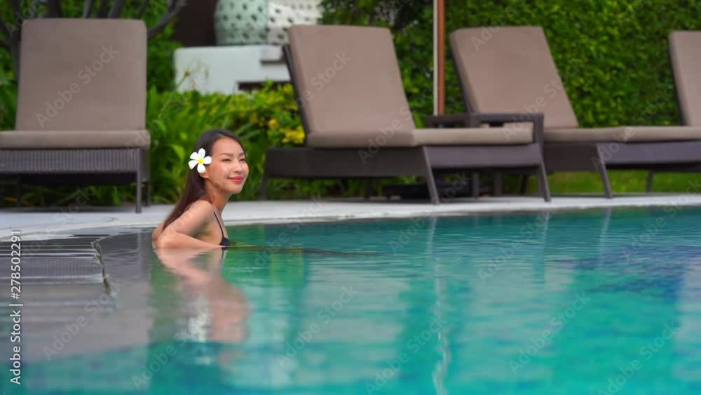 A beautiful lady sitting in a pool wearing a flower in her hair while smiling with the ocean behind her A beautiful lady sitting in a pool wearing a flower in her hair while smiling with the ocean behind her