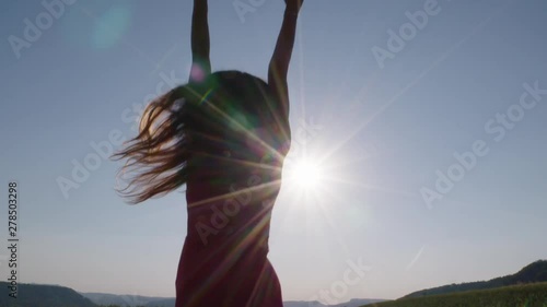 a woman jumping in the air in front of the sun photo