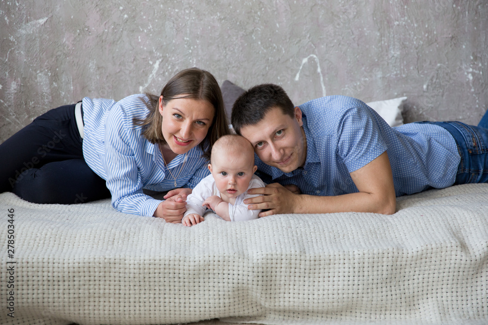 Happy Young Caucasian Family Lying on Bed