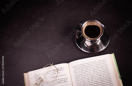 cup of coffee and book on black background