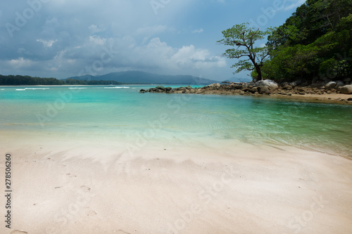 Tropical beach coastline with cloudy sky..Beach on mainland and small island seperated by blue sea canal at layan beach seashore of phuket.