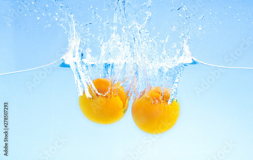 Two ripe oranges falling deeply under water with big splash