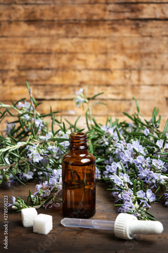 Rosemary oil in a bottle with flower branches