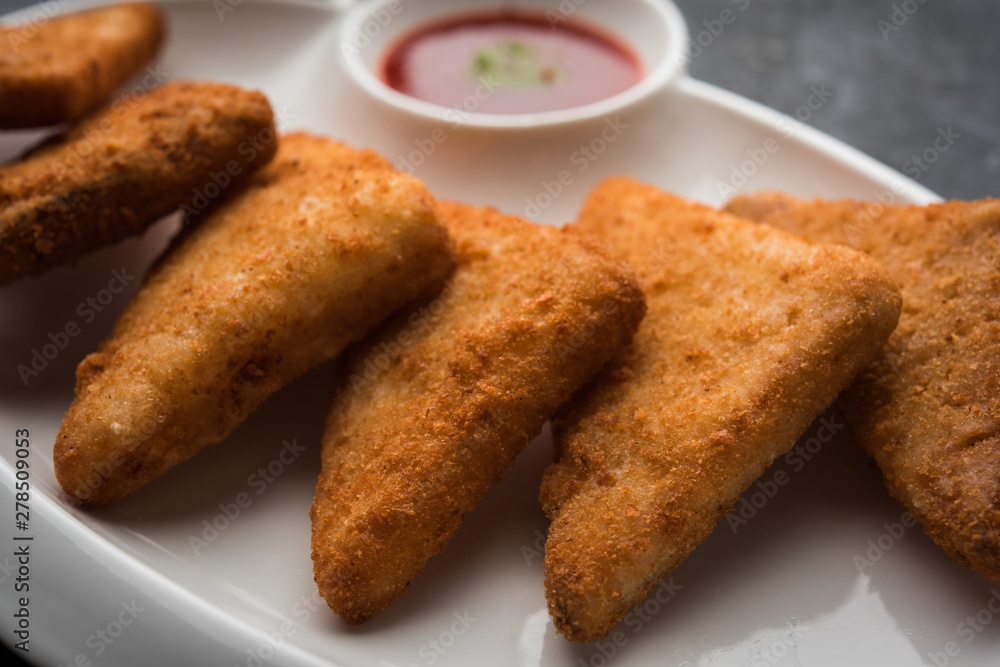 crispy Potato triangles or batata vada covered with bread crumbs and then deep fried. served with tomato ketchup. selective focus crispy Potato triangles or batata vada covered with bread crumbs and then deep fried. served with tomato ketchup. selective focus