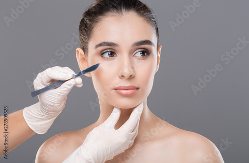 Cosmetologist preparing young woman for plastic surgery procedure