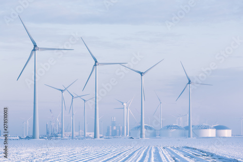 Windmills in a white winter landscape with snow producing green and sustainable energy to reduce global warming - Eemshaven, Groningen, The Netherlands