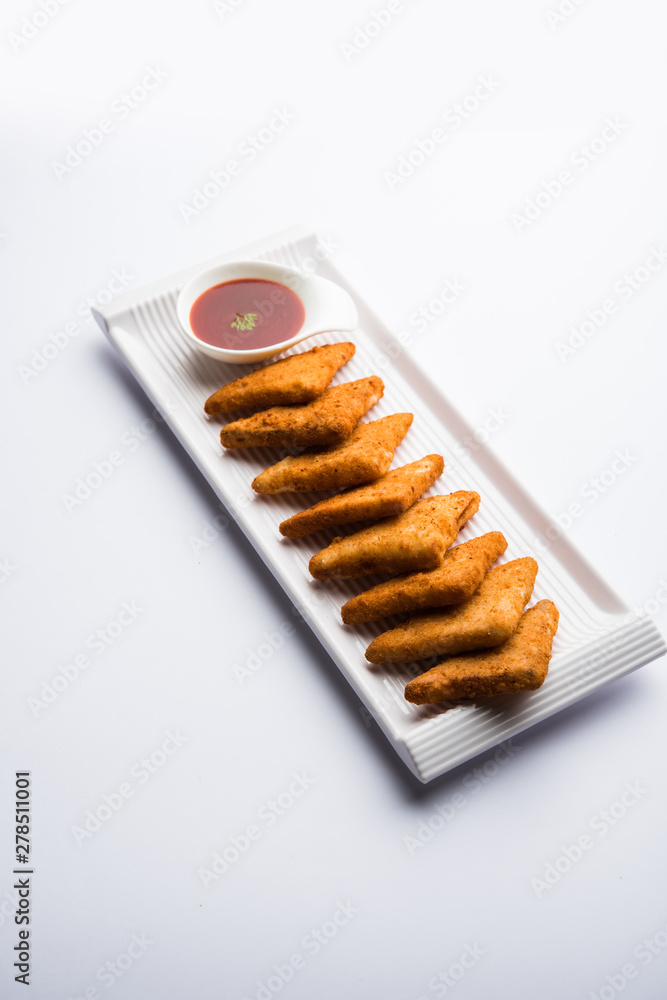 crispy Potato triangles or batata vada covered with bread crumbs and then deep fried. served with tomato ketchup. selective focus crispy Potato triangles or batata vada covered with bread crumbs and then deep fried. served with tomato ketchup. selective focus