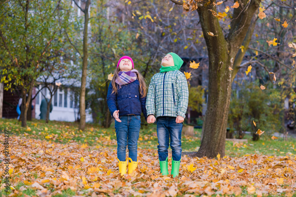 Two children play with maple leaves in park Two children play with maple leaves in park