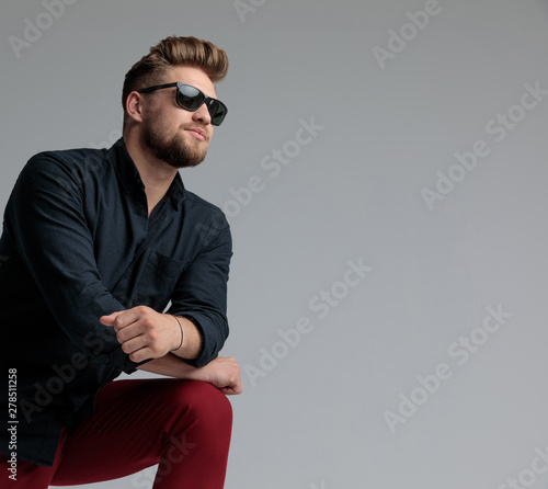 Hopeful casual man leaning on his leg and looking away