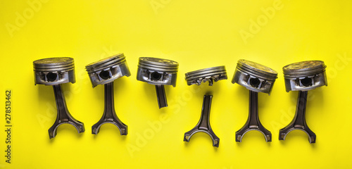 Old broken pistons and connecting rods on yellow background photo