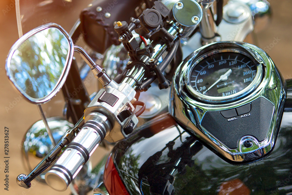Fototapeta premium The chromed handlebar of a motorcycle.Travel and freedom, outdoor activities. View of motorcycle handlebar in the background many motorbikes blurred, concept of speed and travel in nature