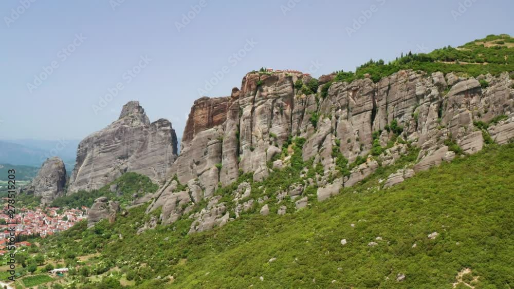 Aerial view of slide turn from drone on panorama of mountain range and roofs of residential buildings. Kalambaka city, Greece. The tops of the rocks of Meteora. Orthodox monasteries Meteora. Aerial view of slide turn from drone on panorama of mountain range and roofs of residential buildings. Kalambaka city, Greece. The tops of the rocks of Meteora. Orthodox monasteries Meteora.