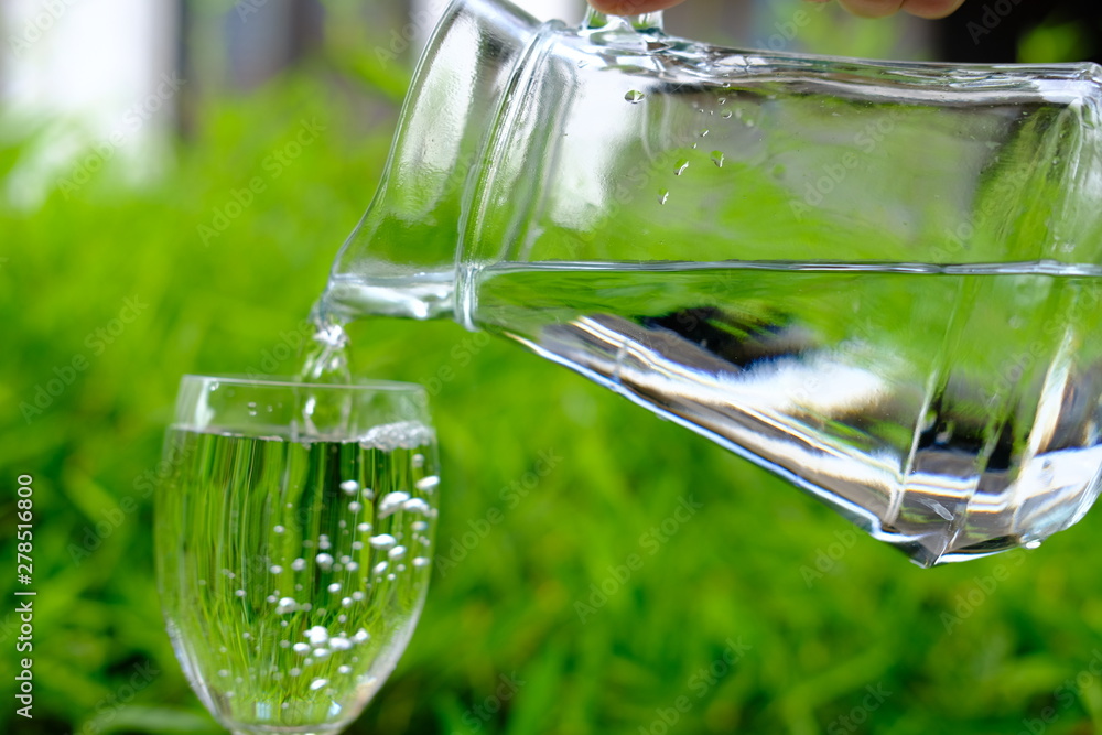 glass of water on background of green grass