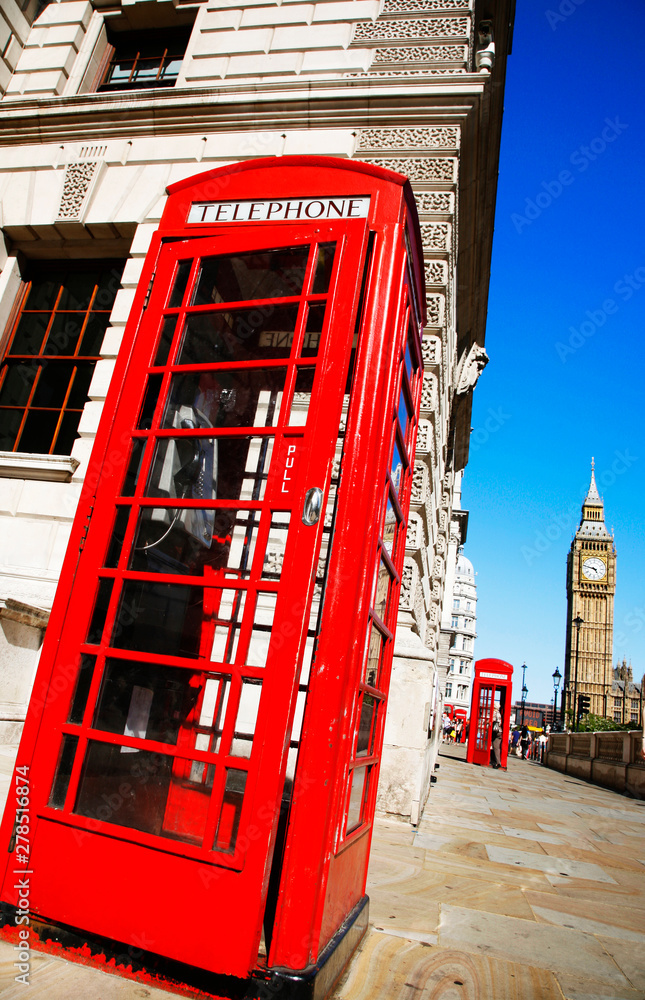 Iconic Red Telephone Booth and Big Ben Clock Tower over blue sky.